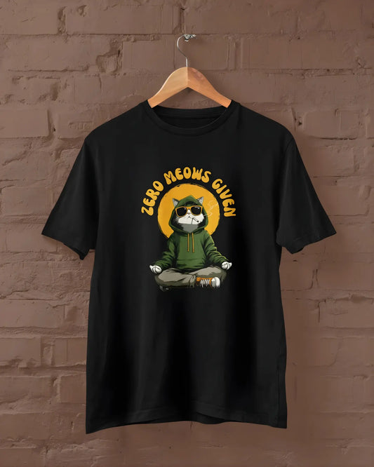 Black t-shirt with a graphic of a cat meditating and 'Zero Meows Given' text, hanging against a brick wall.
