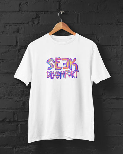 White t-shirt with 'Seek Comfort' text in colorful letters on a black brick wall background.