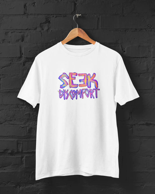 White t-shirt with 'Seek Comfort' text in colorful letters on a black brick wall background.