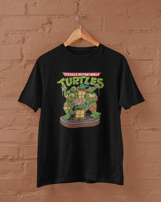 Black t-shirt with Teenage Mutant Ninja Turtles graphic on a hanger against a brick wall.