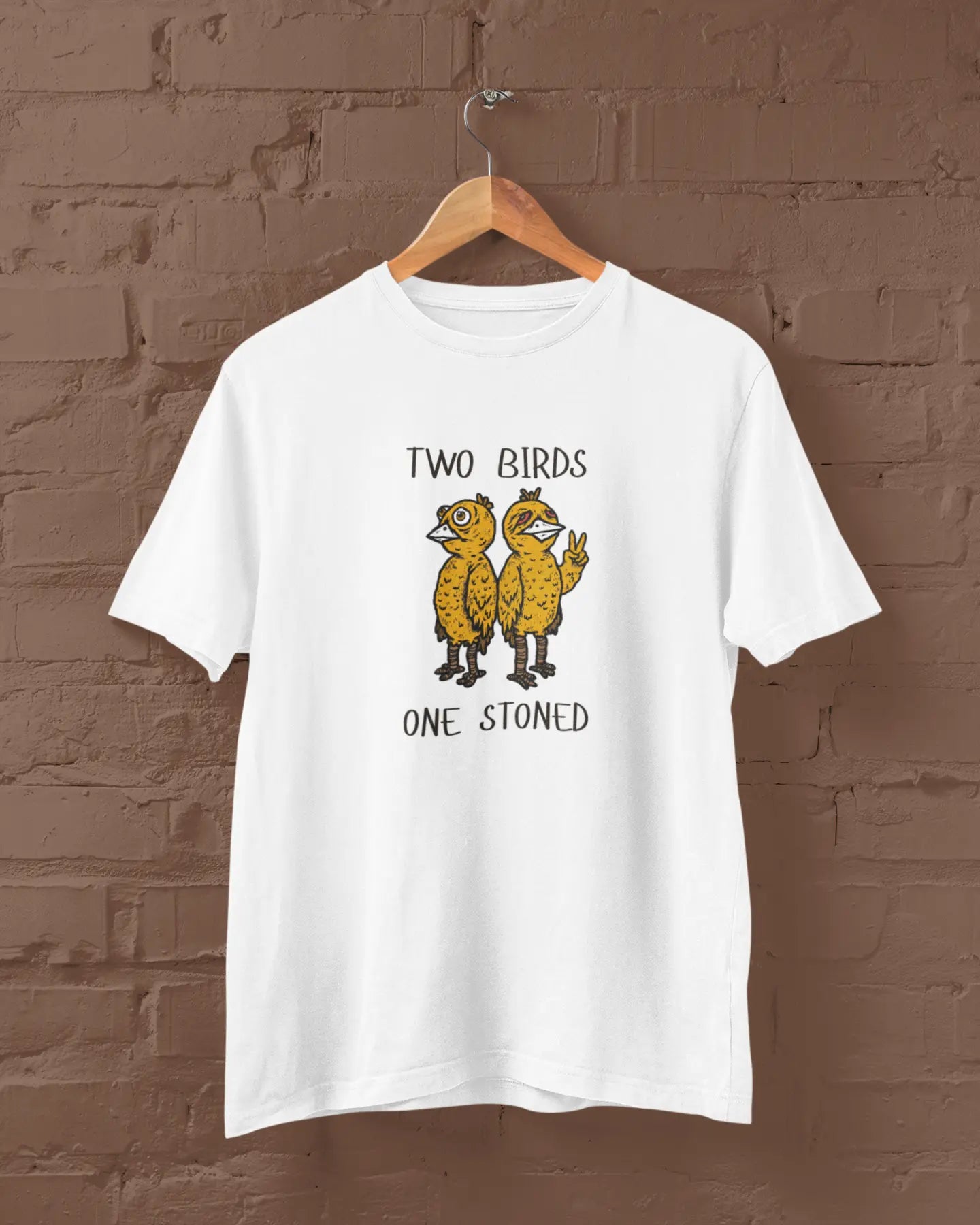 White t-shirt with 'Two Birds One Stoned' graphic on a brown brick wall background