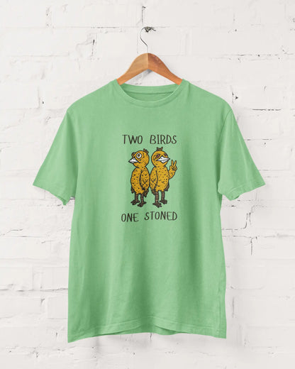 Green t-shirt with 'Two Birds One Stoned' graphic on a white brick wall background