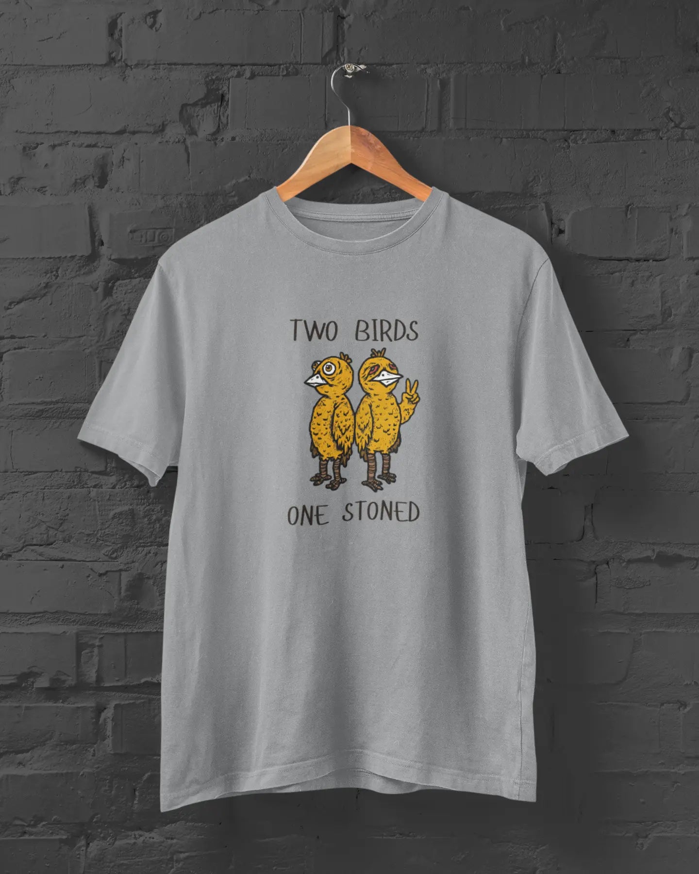 Gray t-shirt with 'Two Birds One Stoned' graphic on a brick wall background