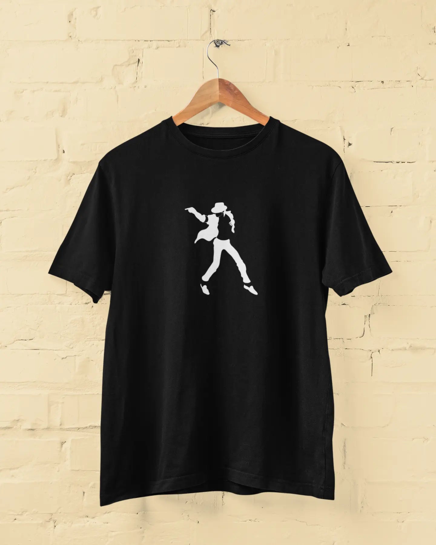 Black michael jackson t-shirt with a white graphic of a person on a wooden hanger against a beige brick wall.