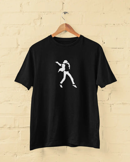 Black michael jackson t-shirt with a white graphic of a person on a wooden hanger against a beige brick wall.